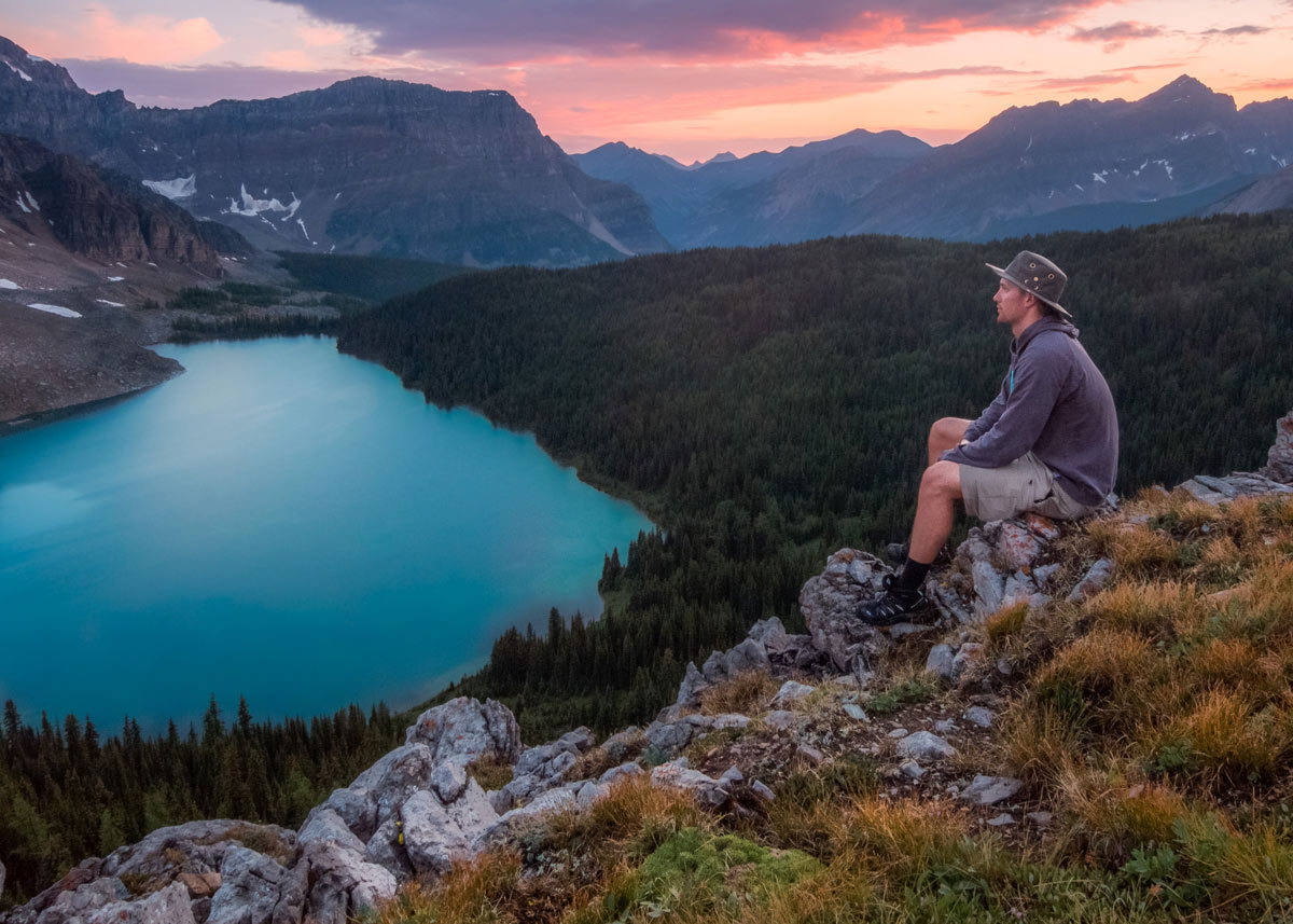 人坐在大自然的岩石上，望着山和湖