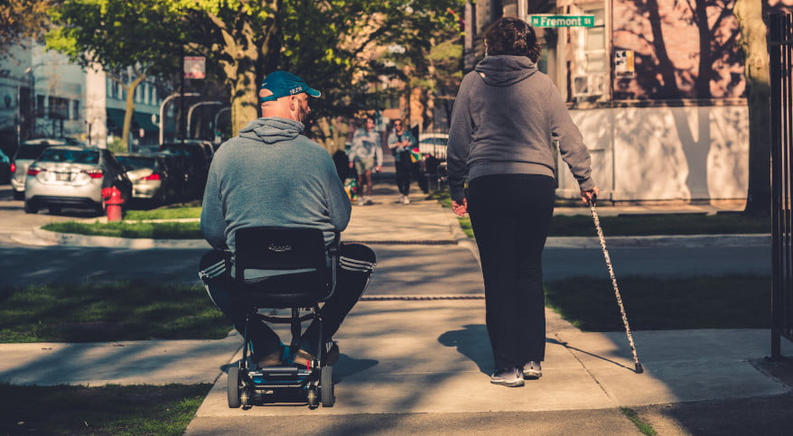 坐轮椅的男人和盲人女人走在街上