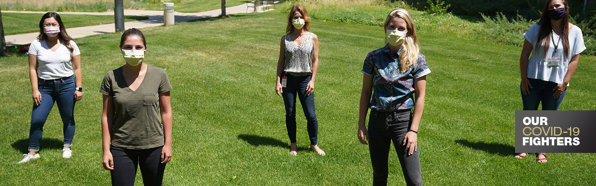 学生们戴着面具在绿色草坪上摆姿势